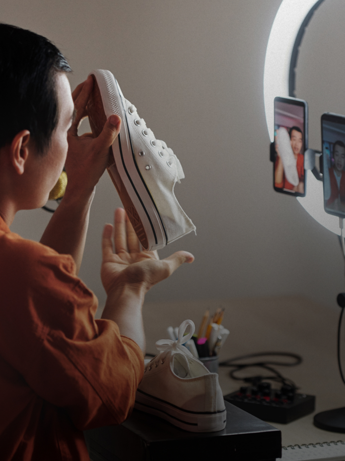 Person holding up a shoe to show the camera with ring light illuminating them.
